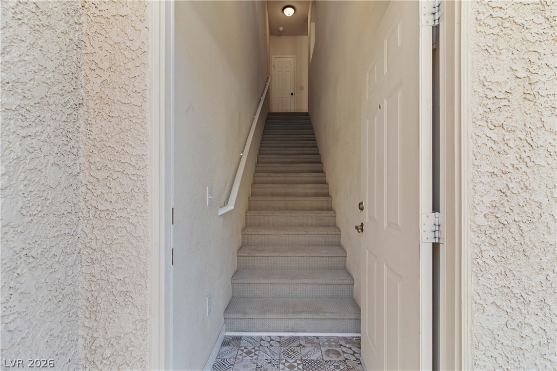 10550 West Alexander Road, Unit 2060 Las Vegas, NV 89129 - Photo 9 of 45 A welcoming entryway with patterned tile flooring leads to a carpeted staircase with a modern handrail.