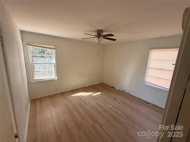 an empty room with windows and fan
