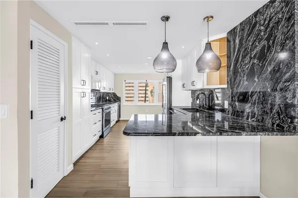 a kitchen with stainless steel appliances kitchen island granite countertop a refrigerator a oven a stove and a sink with granite countertops