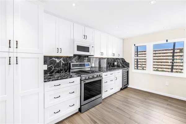 a kitchen with granite countertop white cabinets and white appliances