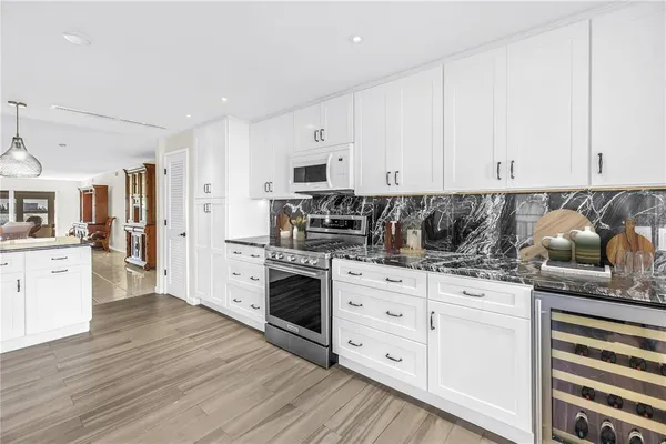 a kitchen with granite countertop a sink cabinets stainless steel appliances and wooden floor