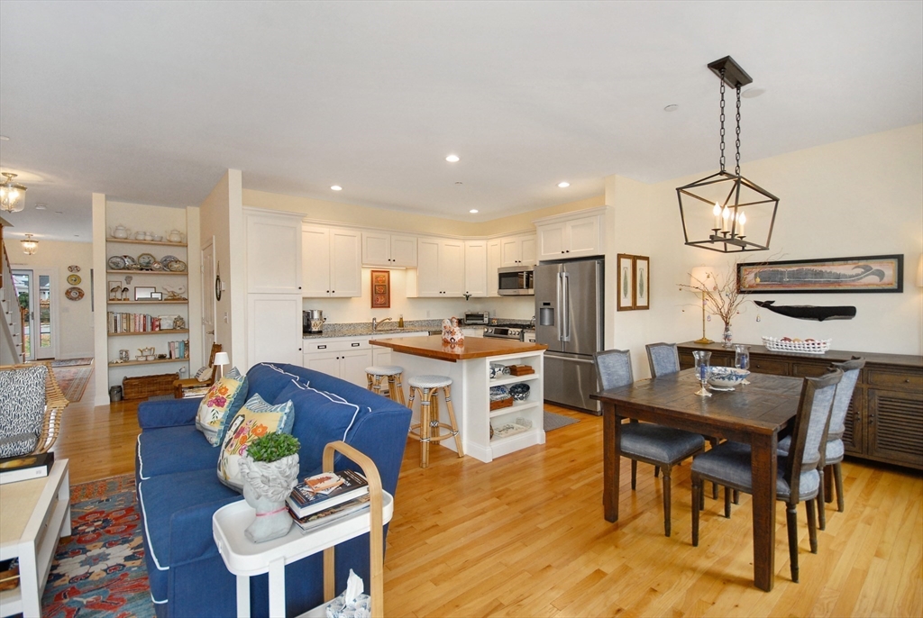 22 B Blacksmith Row, Unit B Groton, MA 01450 - Photo 11 of 24 a kitchen with stainless steel appliances kitchen island granite countertop a table chairs and a living room