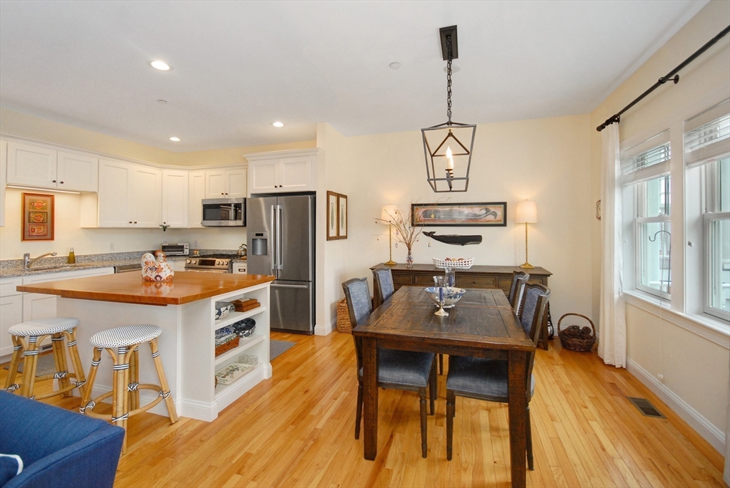 22 B Blacksmith Row, Unit B Groton, MA 01450 - Photo 12 of 24 a kitchen with a refrigerator a stove a sink dishwasher a dining table and chairs with wooden floor