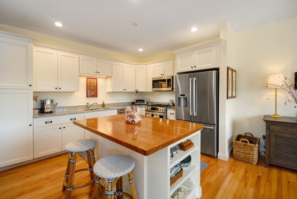22 B Blacksmith Row, Unit B Groton, MA 01450 - Photo 16 of 24 a kitchen with stainless steel appliances granite countertop a sink a stove a refrigerator and island