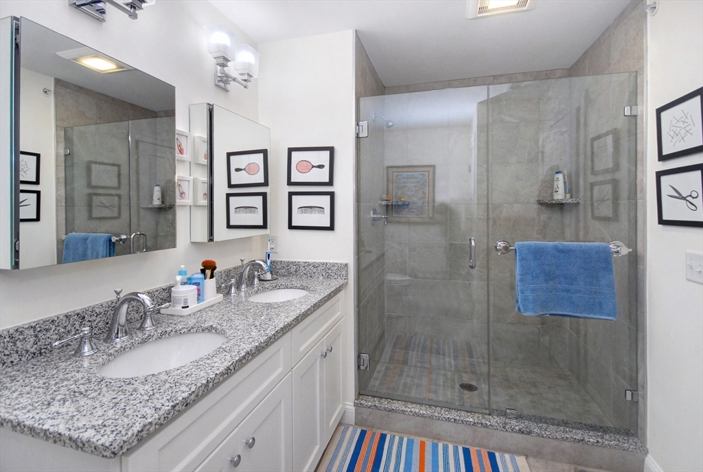 22 B Blacksmith Row, Unit B Groton, MA 01450 - Photo 18 of 24 a bathroom with a granite countertop sink a mirror and shower