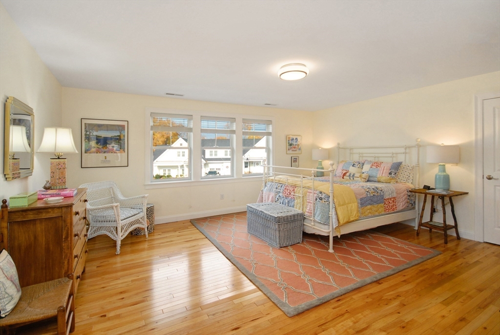 22 B Blacksmith Row, Unit B Groton, MA 01450 - Photo 21 of 24 a bedroom with furniture and a wooden floor