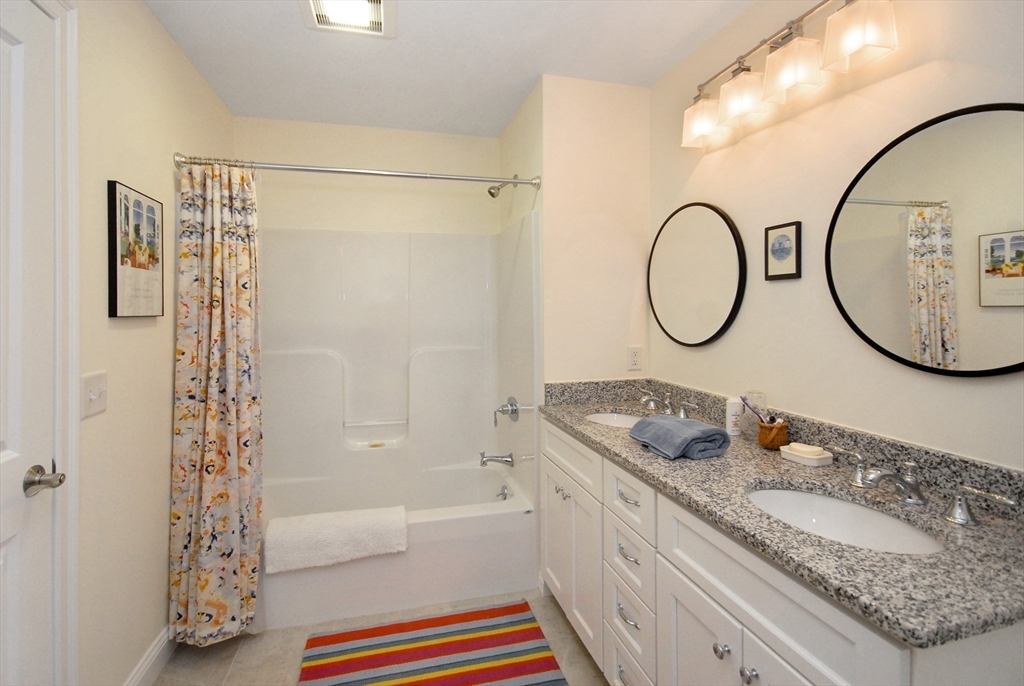22 B Blacksmith Row, Unit B Groton, MA 01450 - Photo 22 of 24 a bathroom with a granite countertop sink mirror vanity and a shower
