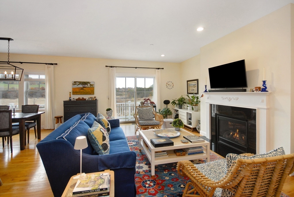 22 B Blacksmith Row, Unit B Groton, MA 01450 - Photo 7 of 24 a living room with furniture a flat screen tv and a fireplace