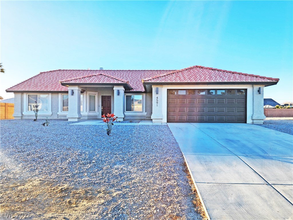 4591 Stoneham Street Pahrump, NV 89061 - Photo 1 of 42 A terracotta-tiled roof crowns this residence, featuring an attached garage and a neatly paved driveway.