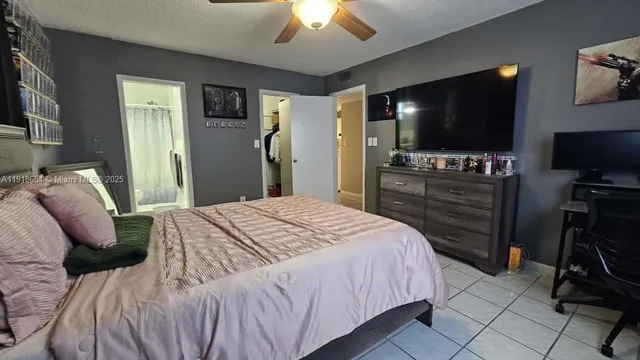 a bedroom with a bed and a flat tv screen on dresser