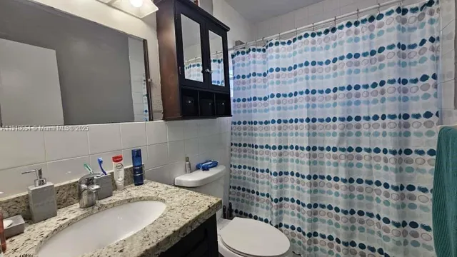 a bathroom with a granite countertop sink a toilet and shower curtain