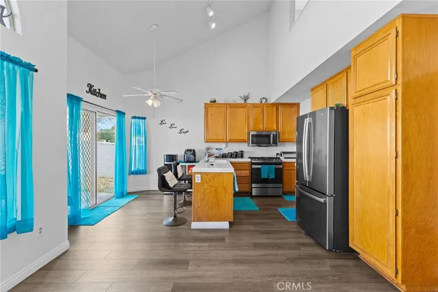 a kitchen with a refrigerator a stove top oven a sink and a dining table with wooden floor