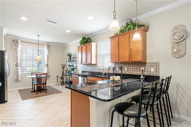a kitchen with granite countertop a sink a stove a dining table and chairs
