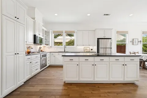 a kitchen with granite countertop white cabinets white appliances a sink and a window