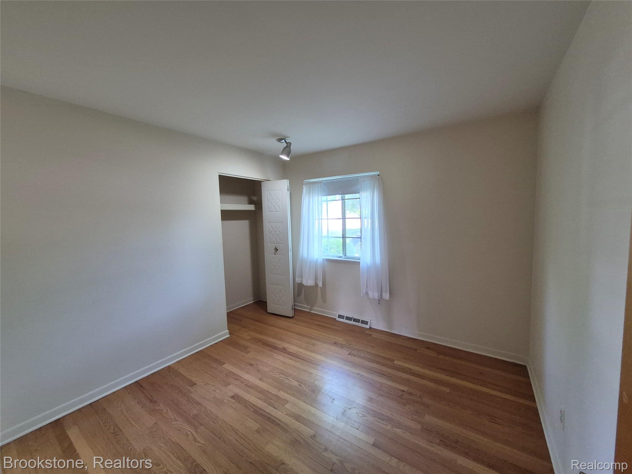4295 Sashabaw Road Waterford, MI 48329 - Photo 24 of 37 Hardwood flooring throughout, featuring a window with natural light, a bi-fold closet, and neutral wall tones