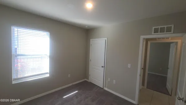 a view of an empty room with closet and a window