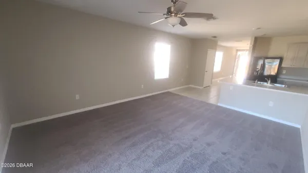 en empty room with windows and chandelier fan