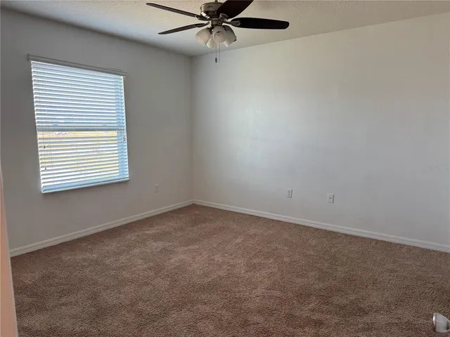 an empty room with a window and a fan
