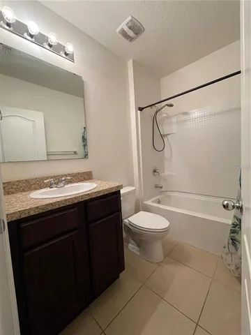 a bathroom with a granite countertop bathtub shower sink vanity and toilet