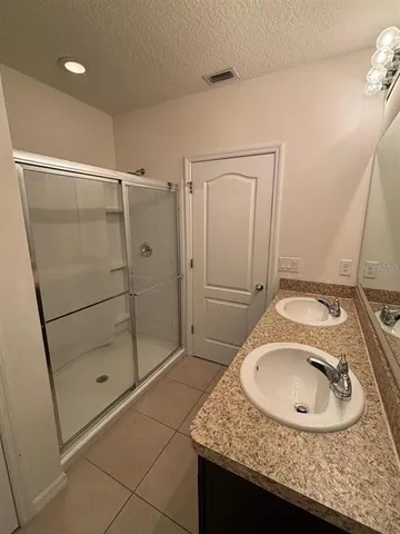 a bathroom with a granite countertop sink a mirror and shower