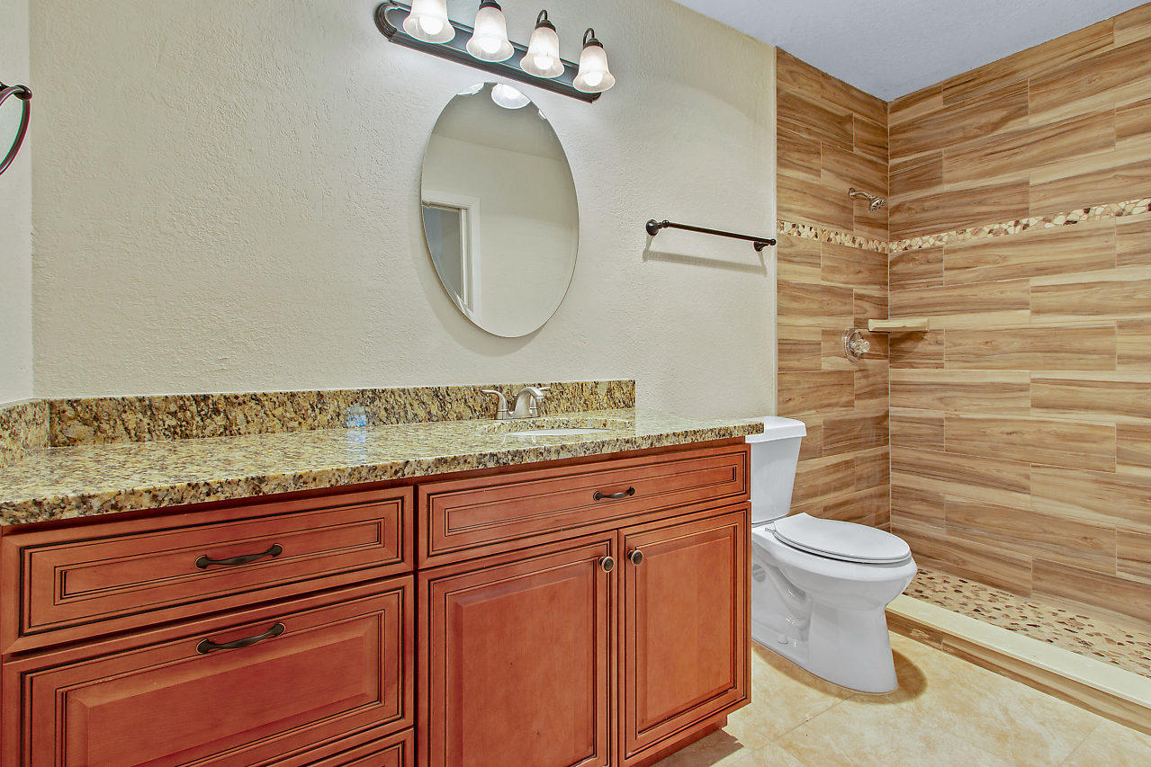 5903 Southeast Mitzi Lane Stuart, FL 34997 - Photo 13 of 22 a bathroom with a granite countertop toilet sink and mirror