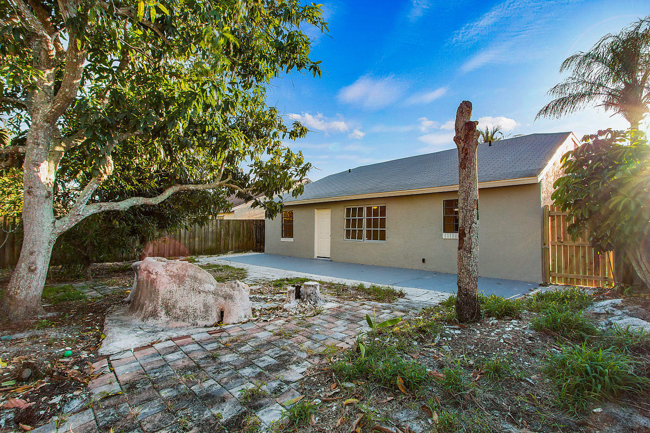5903 Southeast Mitzi Lane Stuart, FL 34997 - Photo 21 of 22 a backyard of a house with table and chairs