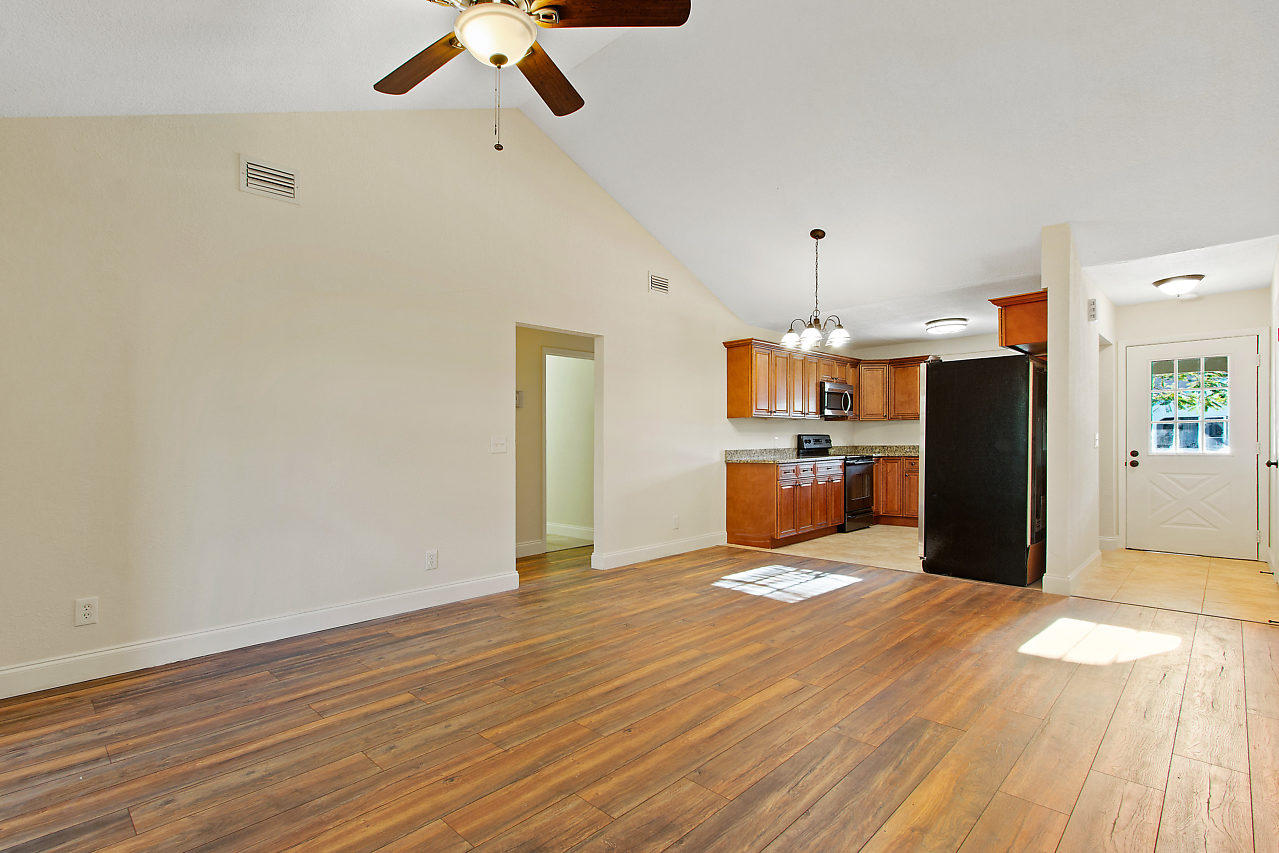 5903 Southeast Mitzi Lane Stuart, FL 34997 - Photo 9 of 22 a large kitchen with a wooden floor and white appliances