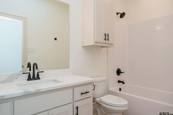 an empty room with wooden floor ceiling fan and windows