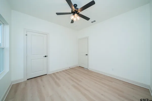 an empty room with wooden floor kitchen view and a window