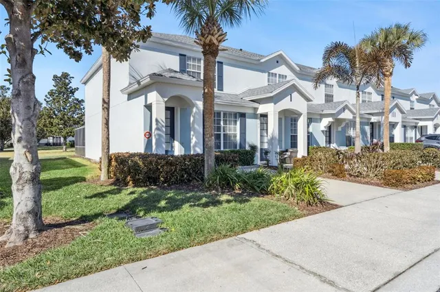 a front view of a house with a garden and palm trees