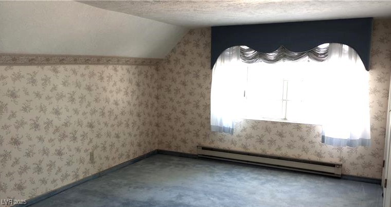 316 Cedar Street Pioche, NV 89043 - Photo 11 of 15 Bedroom with wallpapered walls, a textured ceiling, vaulted ceiling, and a baseboard radiator