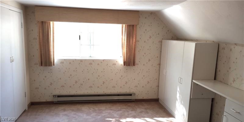 316 Cedar Street Pioche, NV 89043 - Photo 14 of 15 Additional living space with wallpapered walls, a baseboard radiator, vaulted ceiling, and light colored carpet