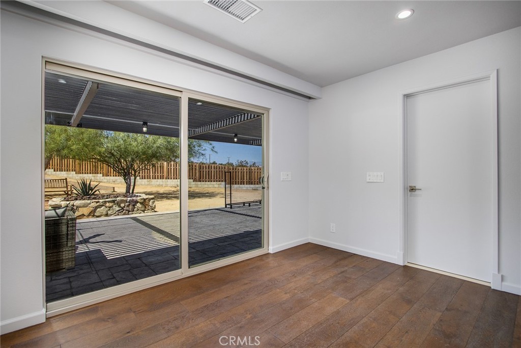 7320 Sherwood Road Joshua Tree, CA 92252 - Photo 14 of 44 a view of an empty room with wooden floor and a window