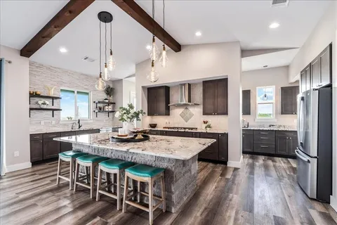 a large kitchen with granite countertop lots of counter space dining table and stainless steel appliances