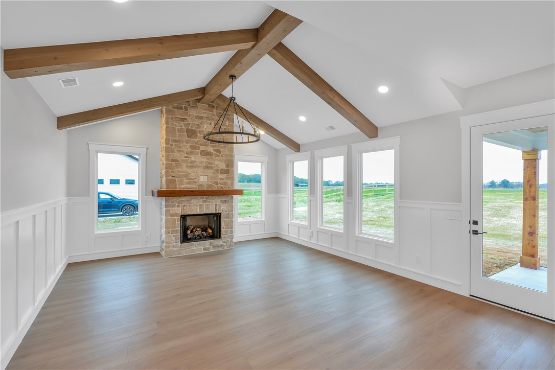 4554 Flat Rock Road Iva, SC 29655 - Photo 8 of 32 A spacious great room featuring exposed wood beams and a natural stone fireplace, illuminated by an array of tall windows.