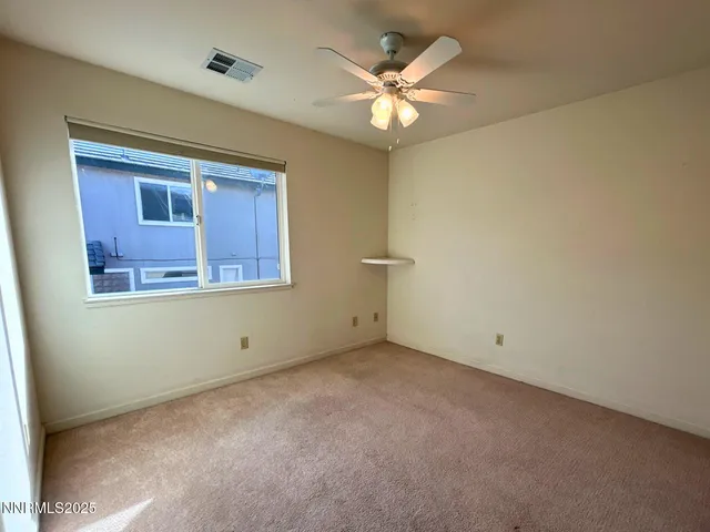 an empty room with a chandelier fan and windows