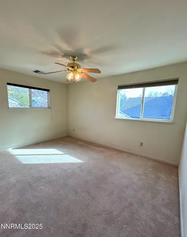 an empty room with windows and fan