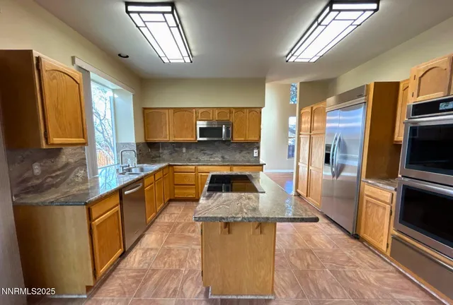 a kitchen with stainless steel appliances granite countertop a refrigerator a stove top oven and sink