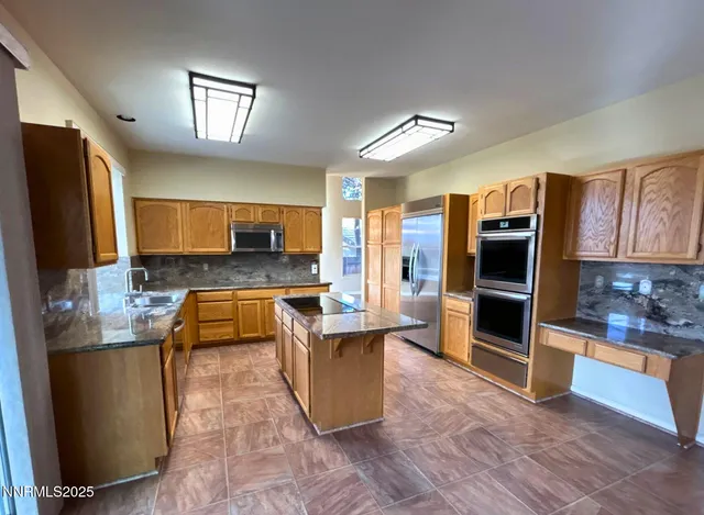 a kitchen with stainless steel appliances granite countertop a refrigerator a stove and a sink