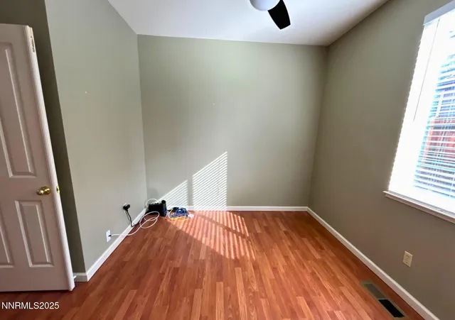 a view of empty room with wooden floor and window
