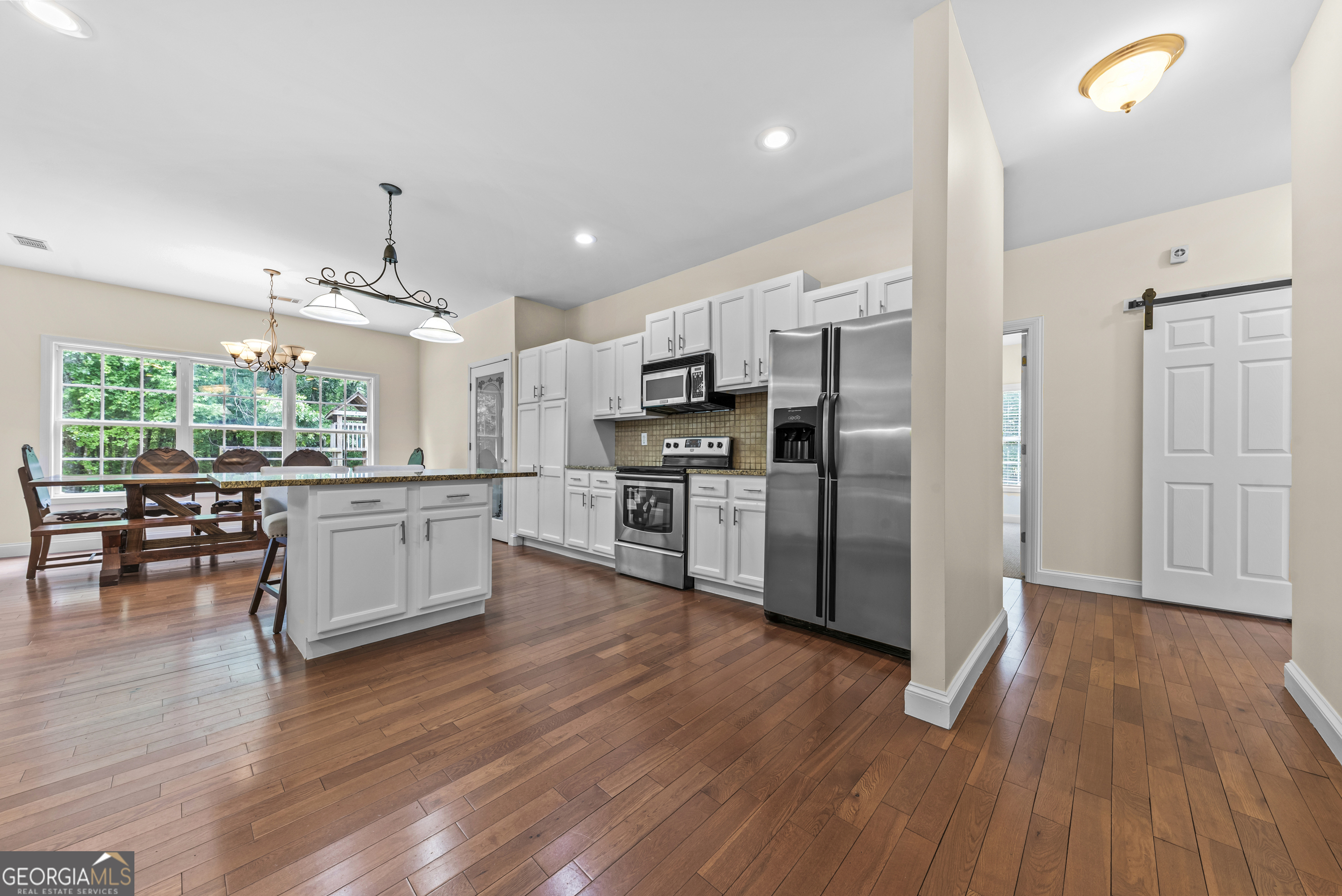 180 Cooper Road Social Circle, GA 30025 - Photo 21 of 51 a kitchen with stainless steel appliances kitchen island wooden floors cabinets and dining table