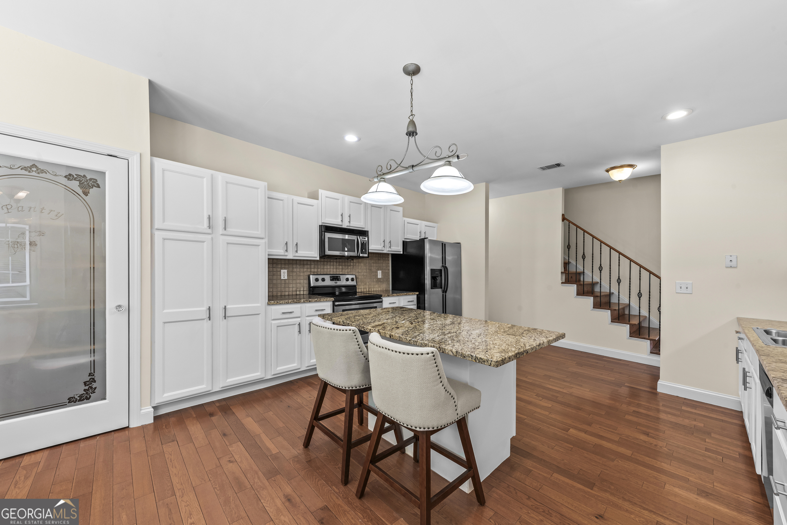 180 Cooper Road Social Circle, GA 30025 - Photo 25 of 51 a kitchen with stainless steel appliances a dining table chairs a refrigerator and cabinets