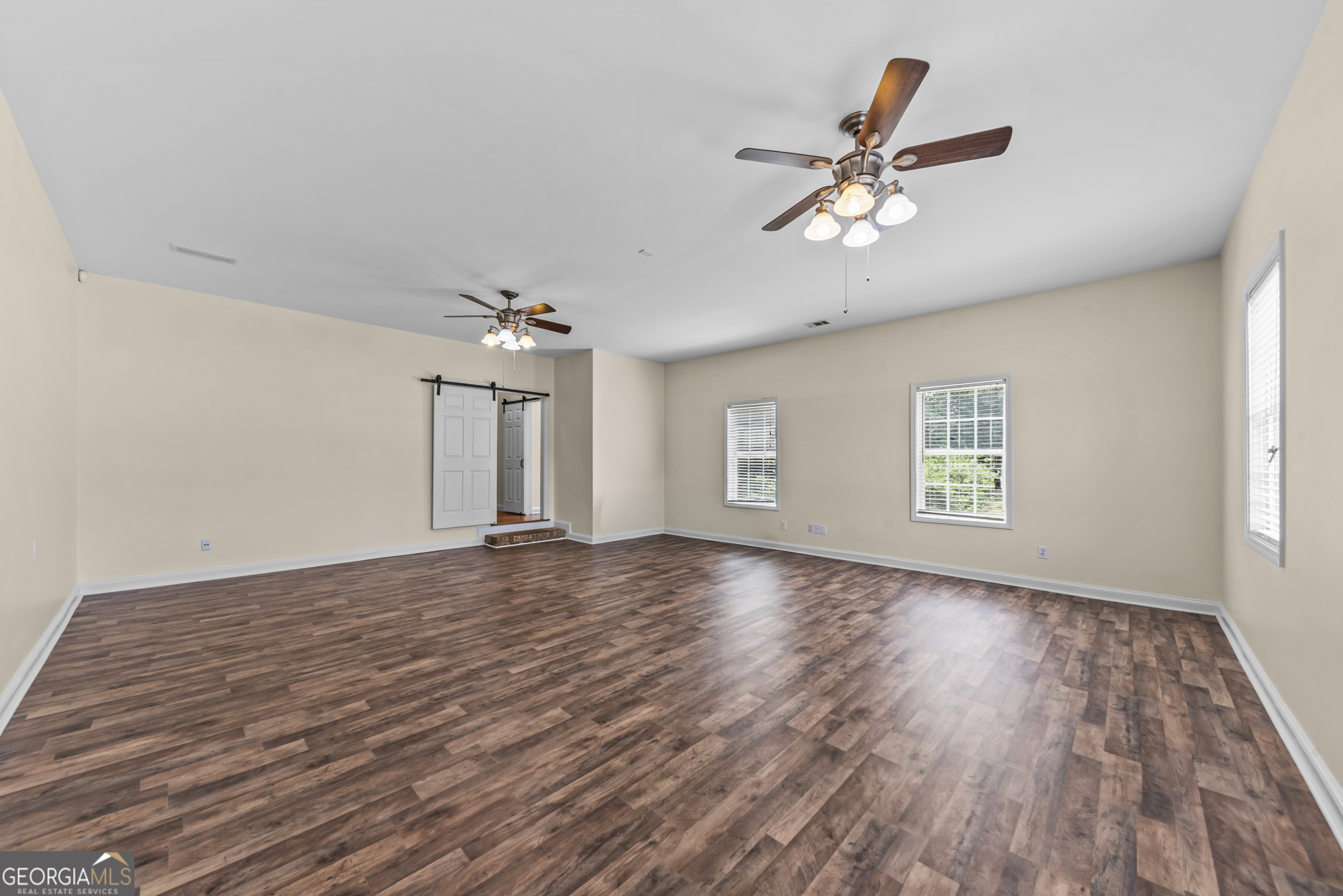 180 Cooper Road Social Circle, GA 30025 - Photo 45 of 51 an empty room with wooden floor chandelier fan and windows