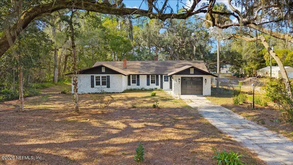 a front view of house with yard and trees in the background