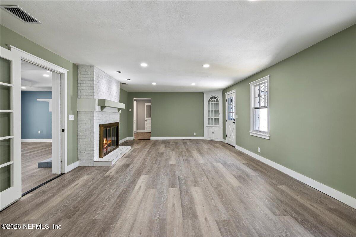242 Taylor Fury Road Pomona Park, FL 32181 - Photo 4 of 40 an empty room with wooden floor and a fireplace