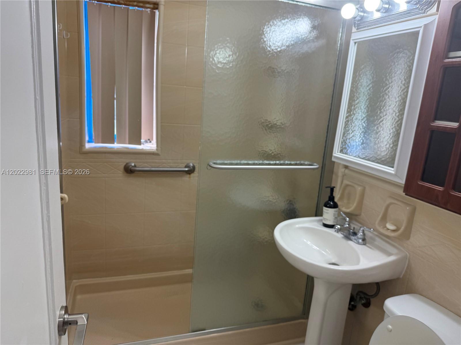 5940 Southwest 2nd Street Miami, FL 33144 - Photo 18 of 22 a bathroom with a sink a mirror and a shower