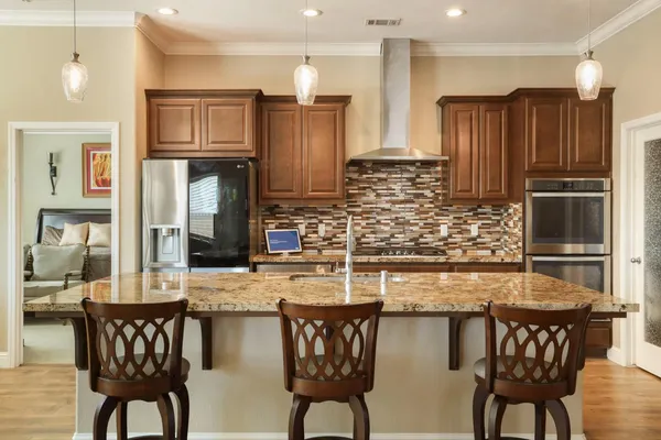 a kitchen with stainless steel appliances granite countertop a kitchen island a stove and a refrigerator