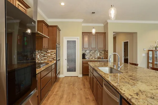 a kitchen with stainless steel appliances granite countertop a refrigerator a sink and wooden cabinets