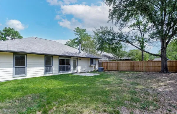 a view of a house with a yard and large tree