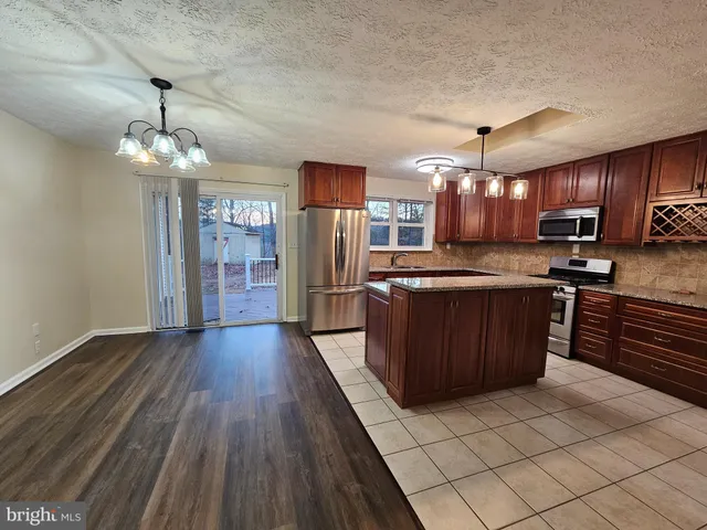 a large kitchen with stainless steel appliances granite countertop a stove and a wooden cabinets